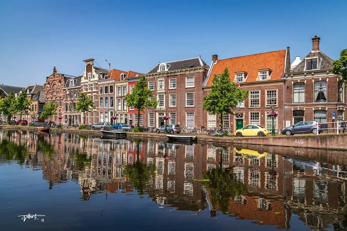 Leiden Üniversitesi ve Tarihi Hollanda Mimarisi Leiden Üniversitesi, Hollanda’nın en eski ve köklü üniversitesi olarak tarihi şehir manzarasıyla öne çıkmaktadır. Fotoğrafta, Leiden kentinin kanalları boyunca sıralanan geleneksel Hollanda evleri, suya yansıyan mimari güzellikleriyle görülmektedir.