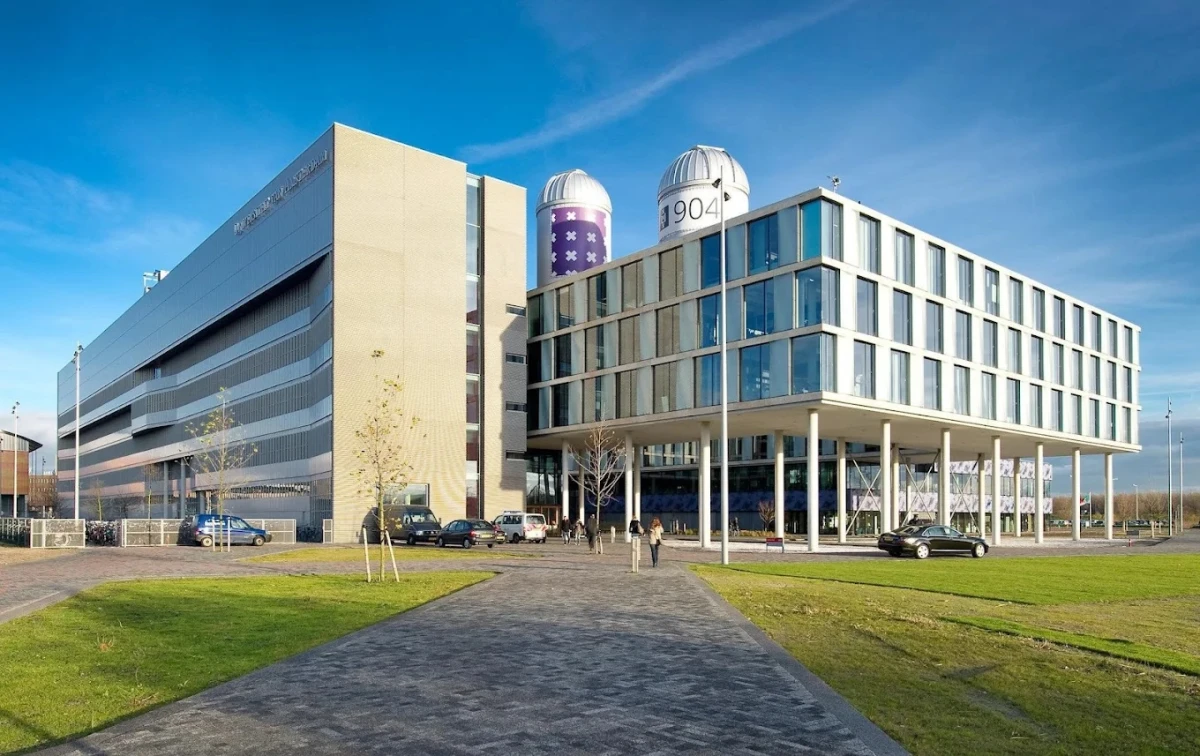 Amsterdam Üniversitesi Modern Kampüs ve Araştırma Merkezi Amsterdam Üniversitesi, Avrupa’nın en saygın yükseköğretim kurumlarından biri olup modern kampüs binalarıyla dikkat çekmektedir. Fotoğrafta, geniş cam cepheli çağdaş mimari yapılar, gözlemevi kubbeleri ve üniversitenin araştırma merkezleri görülmektedir.