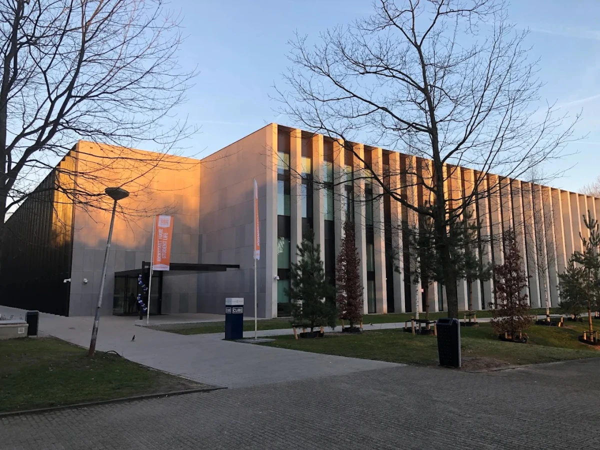 Tilburg Üniversitesi Modern Kampüs Binası Tilburg Üniversitesi, Hollanda’da modern mimarisi ve güçlü akademik programlarıyla öne çıkan prestijli bir yükseköğretim kurumudur. Fotoğrafta üniversitenin çağdaş kampüs binalarından biri, gün batımının yansıttığı sıcak ışıklarla görülmektedir.