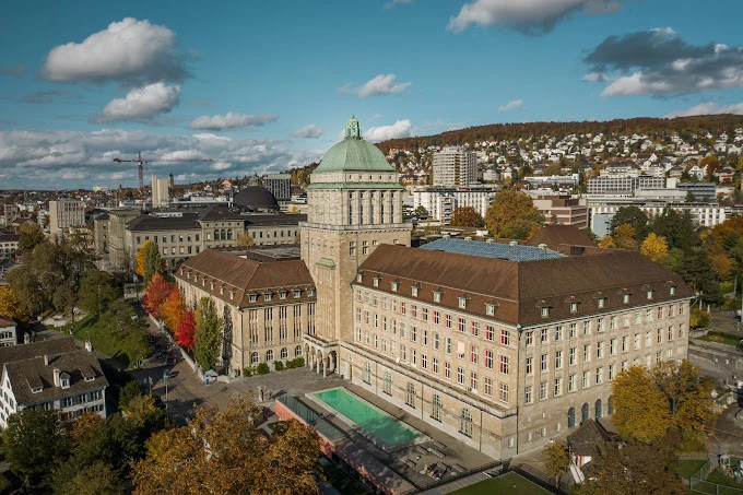 Basel Üniversitesi Tarihi Kampüs ve Şehir Manzarası Basel Üniversitesi, İsviçre’nin en eski üniversitesi olarak köklü tarihi, akademik başarıları ve etkileyici mimarisiyle öne çıkmaktadır. Fotoğrafta üniversitenin şehir merkezine hâkim konumu, tarihi bina yapısı ve çevresindeki doğal güzelliklerle birleşen panoramik şehir manzarası dikkat çekmektedir.