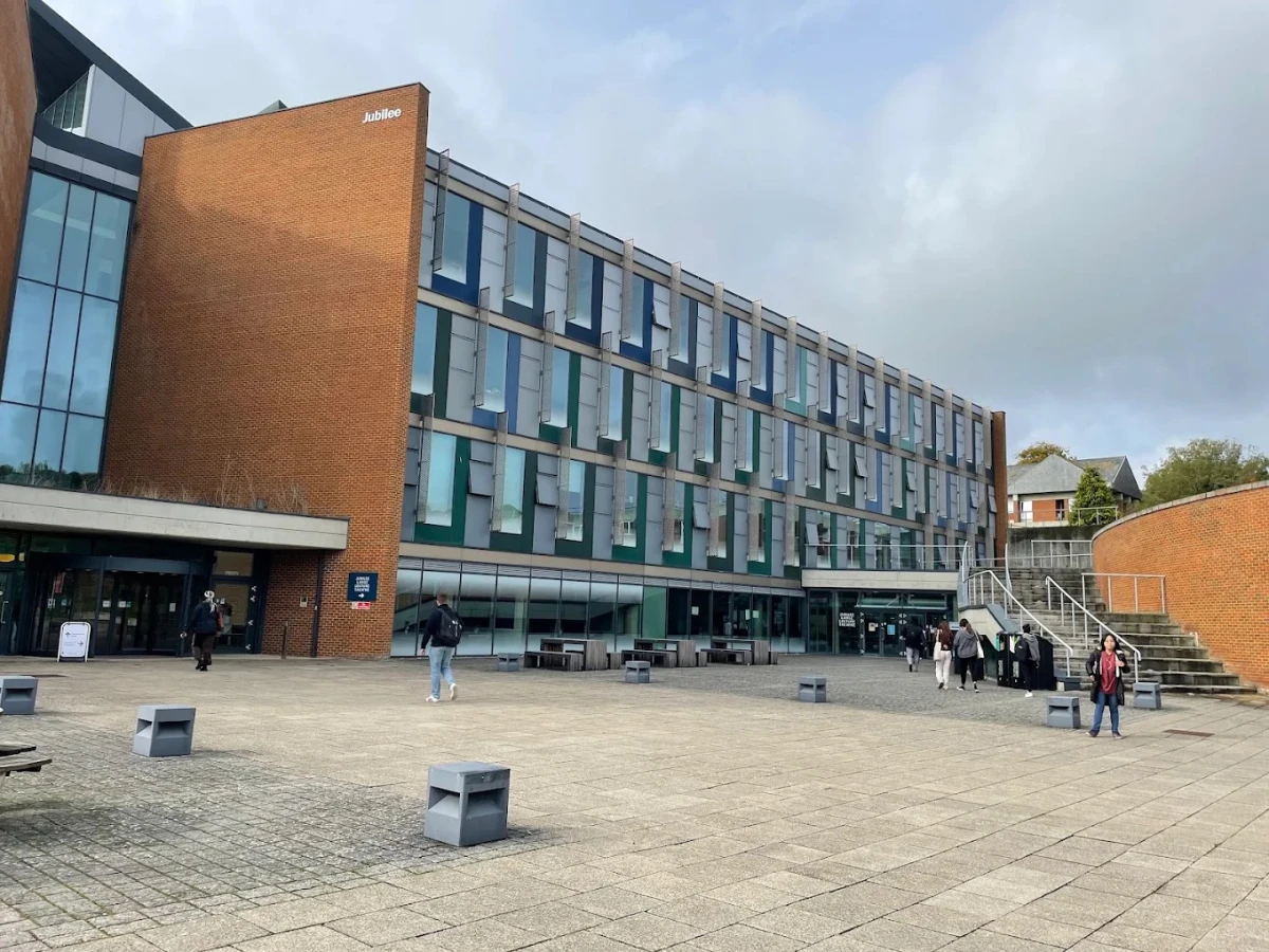 Sussex Üniversitesi Jubilee Binası ve Kampüs Girişi Sussex Üniversitesi Jubilee binası, modern mimarisi ve geniş açık alanlarıyla öğrencilere dinamik bir öğrenim ortamı sunuyor. Kampüsün giriş kısmında öğrenciler hareketlilik içinde eğitim hayatına devam ediyor.