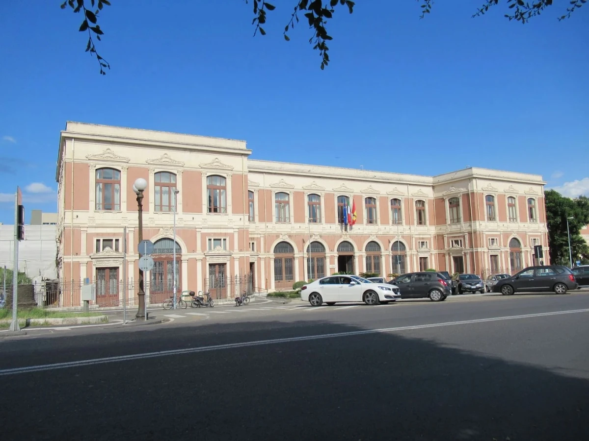 Messina Üniversitesi Ana Binası Messina Üniversitesi, İtalya'nın Messina şehrinde yer alan tarihi ve görkemli ana binasıyla dikkat çekiyor. Bu fotoğrafta, üniversitenin zarif mimari detaylara sahip yapısı, önündeki araçlar ve açık mavi gökyüzü eşliğinde net bir şekilde görülüyor. Akademik mükemmeliyeti ve tarihi dokusuyla öne çıkan Messina Üniversitesi, öğrenciler ve ziyaretçiler için hem eğitim hem de kültürel bir merkez konumunda.